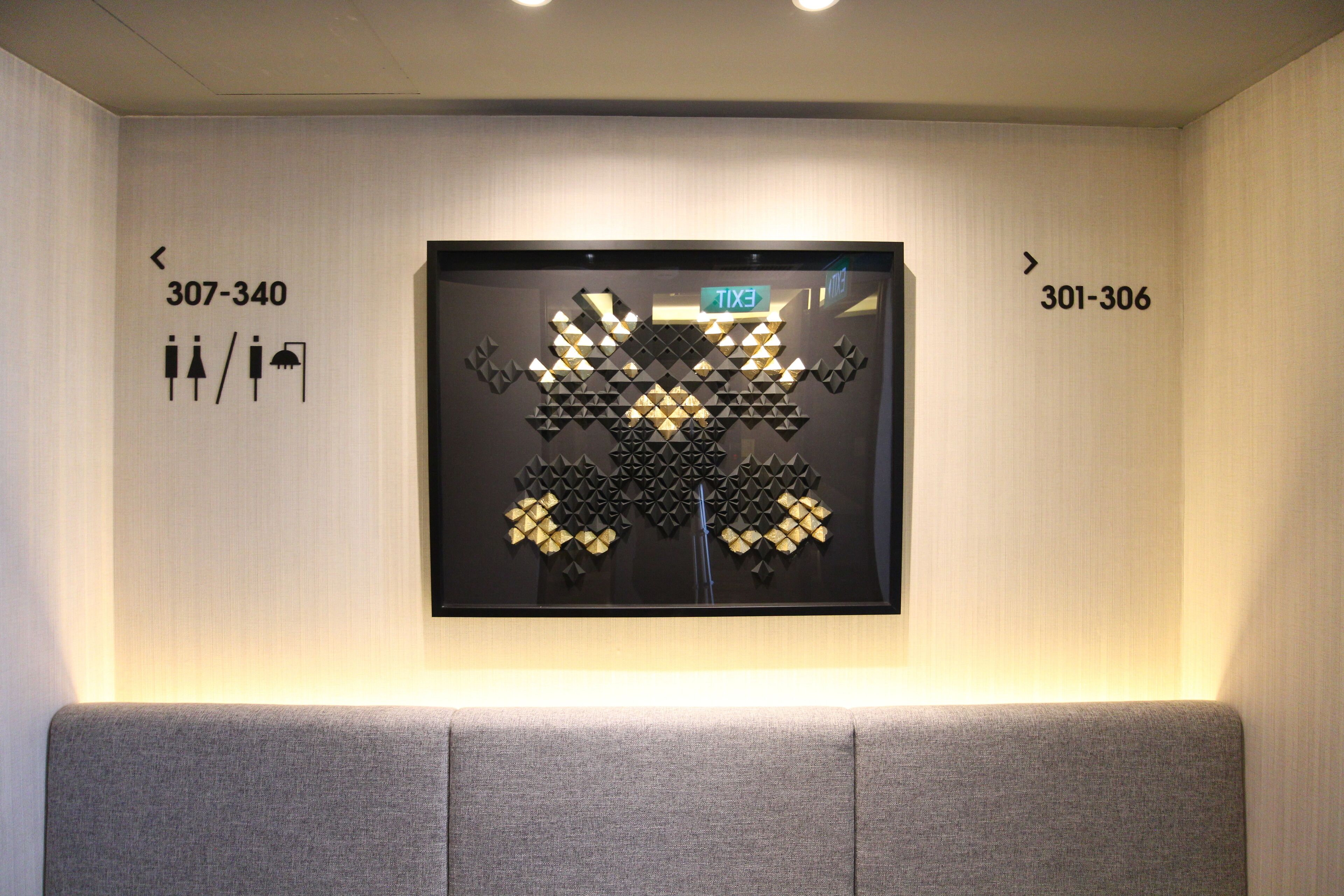A wall-mounted artwork with directional signs and room numbers.
