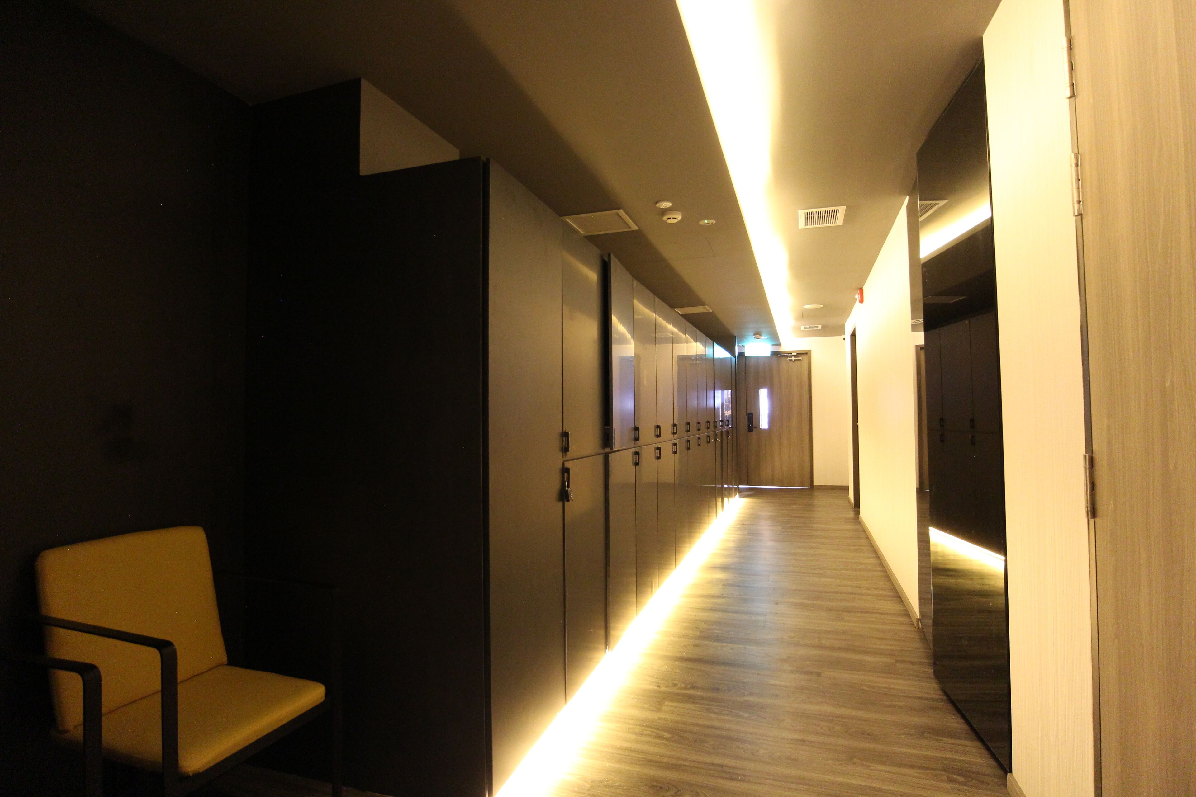 A hallway with lockers, a bench, and a wooden floor.