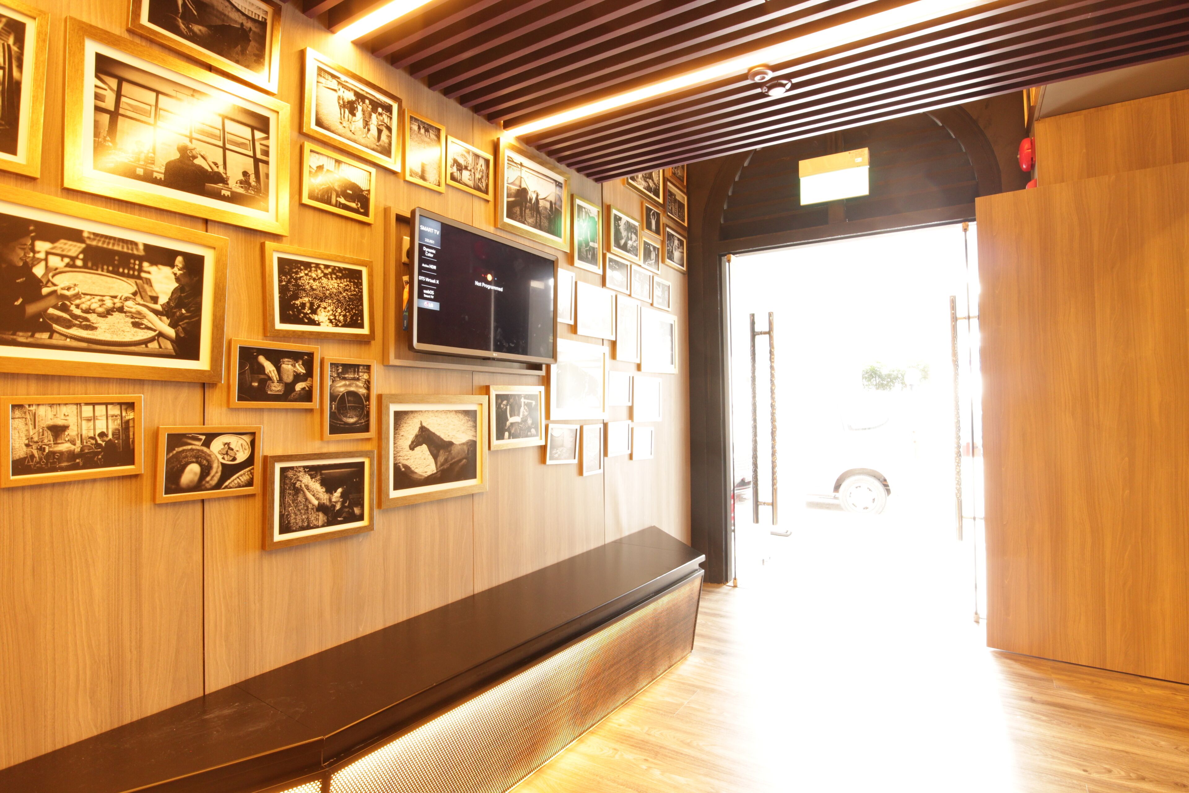 A hallway with wooden paneling, a flat-screen TV, and a bench.