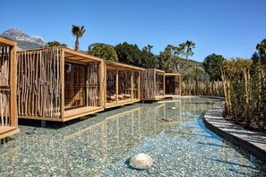 A pool area with wooden structures, clear water, and a pebble ground. - Balmy Beach Resort Kemer - All Inclusive (Kemer)
