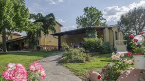 A garden pathway leading to a building with a tiled roof and a covered patio area. - Allodola double bedroom flat facing pool with large veranda (Toscana)