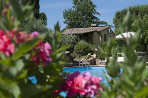 Ein Poolbereich mit freiem Blick auf den Pool, einem Liegestuhl und einem Gebäude mit einem Ziegeldach.
