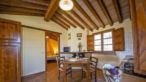 A rustic kitchen with wooden cabinets, a dining table, and a large window. - Allodola double bedroom flat facing pool with large veranda (Toscana)