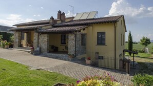 Una casa de dos pisos con fachada de piedra, techo de tejas y un pequeño jardín con plantas en macetas.