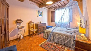 Un dormitorio con cama a dosel, cómoda, silla, espejo y alfombra.