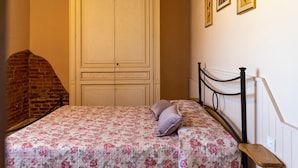 Ein Schlafzimmer mit einem Bett, einer Holzbk, einer Ziegelwand und einem weißen Kleiderschrank.