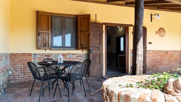 Eine Terrasse im Freien mit Tisch und Stühlen, einer Holztür und einer Ziegelwand.