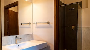 Ein modernes Badezimmer mit einem weißen Waschbecken, einem Spiegel und einer Duschkabine aus Glas.