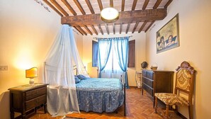 Ein Schlafzimmer mit einem Bett, einem Nachttisch, einer Kommode, einem Sessel und einem Deckenventilator.