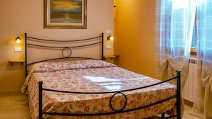 Ein Bett mit einer blumigen Tagesdecke, ein Gemälde an der Wand und zwei Nachttischlampen.