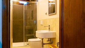 Ein Badezimmer mit einer Duschkabine, einer weißen Toilette und einem weißen Waschbecken mit Spiegel darüber.