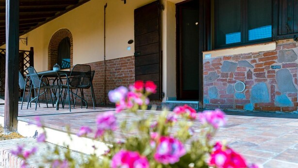 Eine Terrasse im Freien mit Tisch und Stühlen, einer Steinmauer und einer Tür.