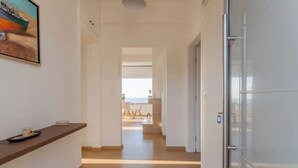 A hallway with a wooden floor, a white door on the right, and a painting on the left. - Steliana's House Top Floor Apartment with Private Jacuzzi (Ligaria)