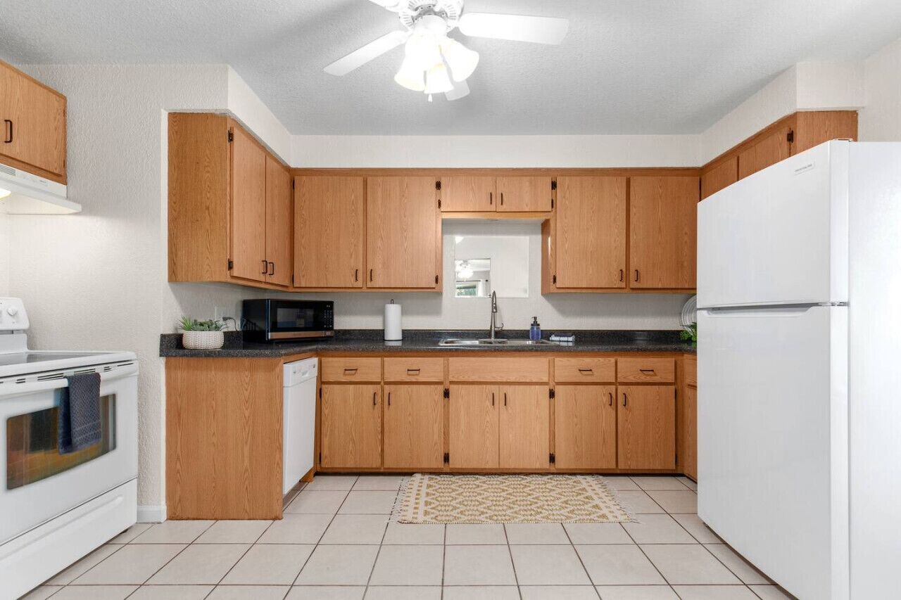 A kitchen with wooden cabinets, a white refrigerator, a microwave, and a stove.