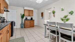 A modern kitchen with wooden cabinets, a dining area with white chairs, and a ceiling fan. - Beautiful & Convenient! (Sheboygan)