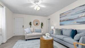 A living room with a ceiling fan, two sofas, a coffee table, and a painting on the wall. - Beautiful & Convenient! (Sheboygan)