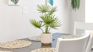 A dining area with a round table, white chairs, a potted plant, and wall-mounted artwork. - Beautiful & Convenient! (Sheboygan)