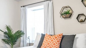 A bedroom with a bed, white curtains, a potted plant, and hexagonal wall decorations. - Beautiful & Convenient! (Sheboygan)