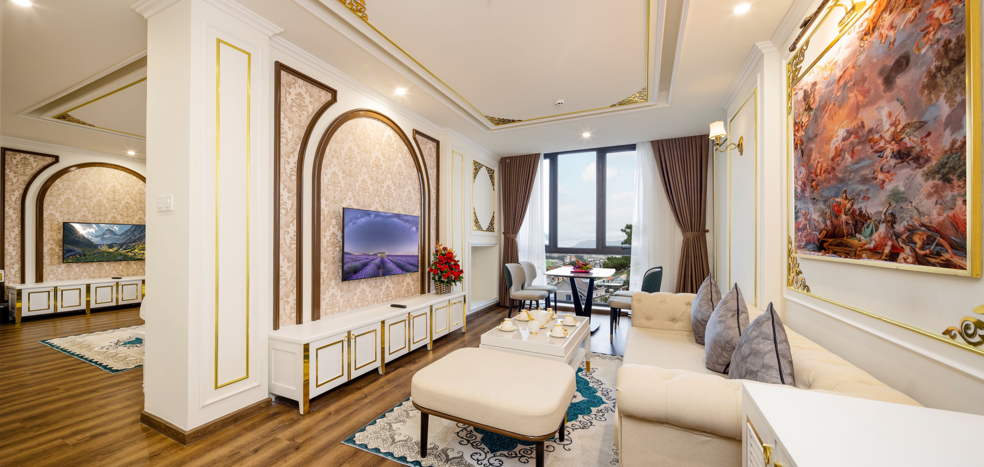 A spacious living room with a large TV, comfortable seating, and a view of the city.
