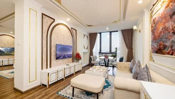 A spacious living room with a large TV, comfortable seating, and a view of the city.