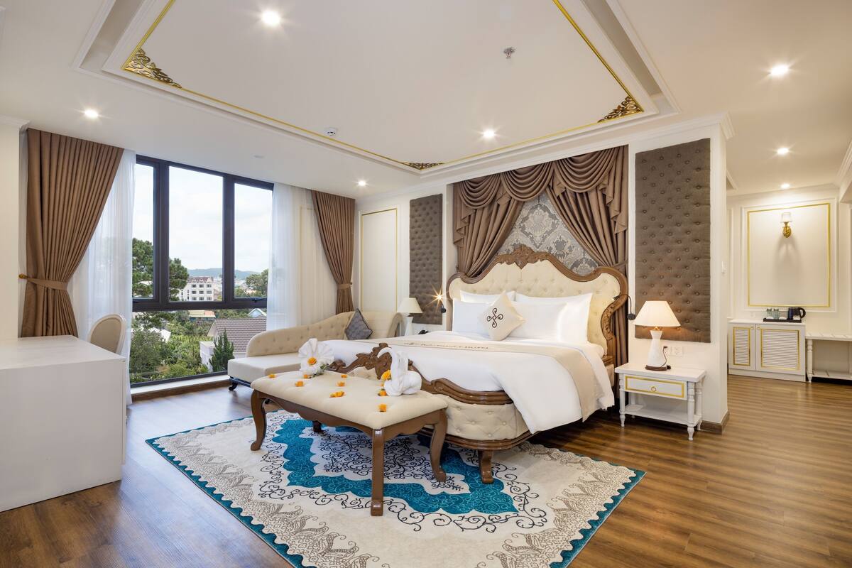 Ein geräumiges Schlafzimmer mit einem großen Bett, einer Sitzecke und Blick auf die Stadt.