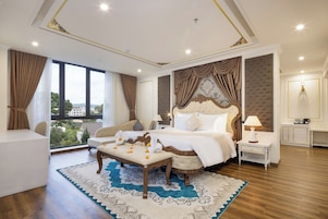 A hotel room with a large bed, a sitting area, and a view of the outdoors.