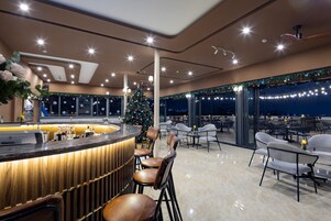 Un bar moderno con un árbol de Navidad, asientos y vistas al cielo nocturno.