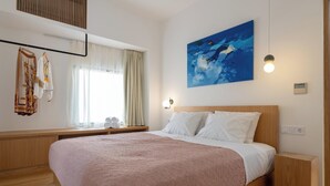 A bedroom with a bed, a window with curtains, a painting, and a bedside table. - Nisi Living Concept - Kasos Villa (Ialysos)