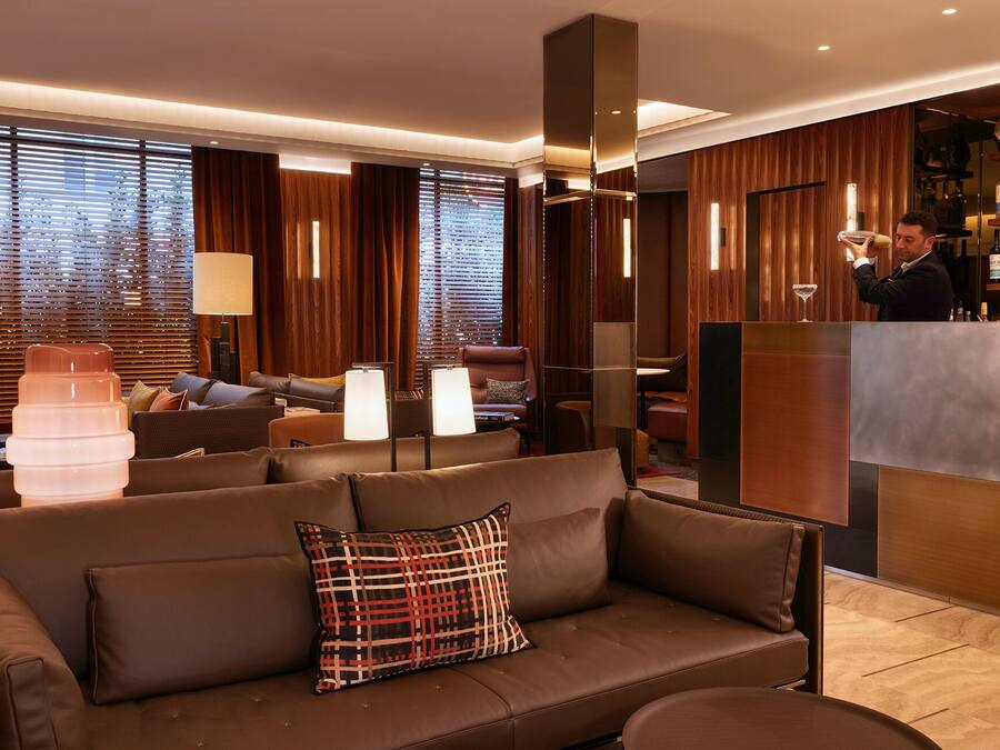 Un moderno vestíbulo de hotel con un sofá de cuero, una zona de bar y paneles de madera.