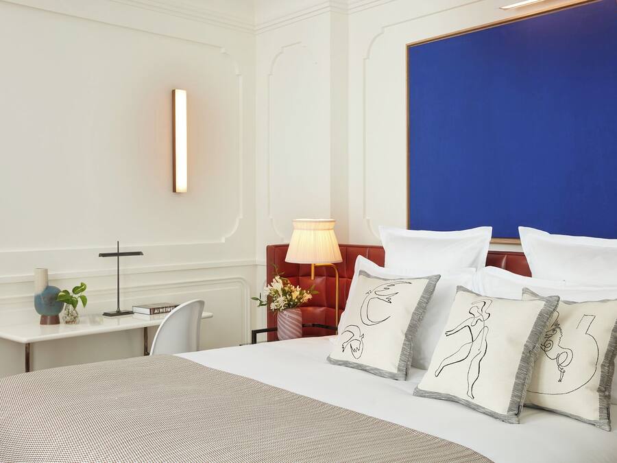 Een hotelkamer met een groot bed, een bureau met een lamp en uitzicht op de stad.