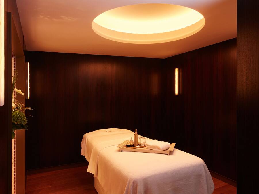 Un cuarto de spa con dos camas, una bandeja con artículos de aseo y una lámpara en el techo.