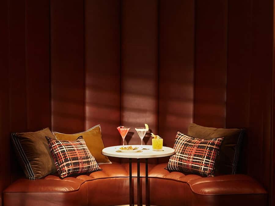 Un'accogliente area salotto con una panca a forma di arco e un piccolo tavolino rotondo, con un bicchiere da martini e un cocktail.