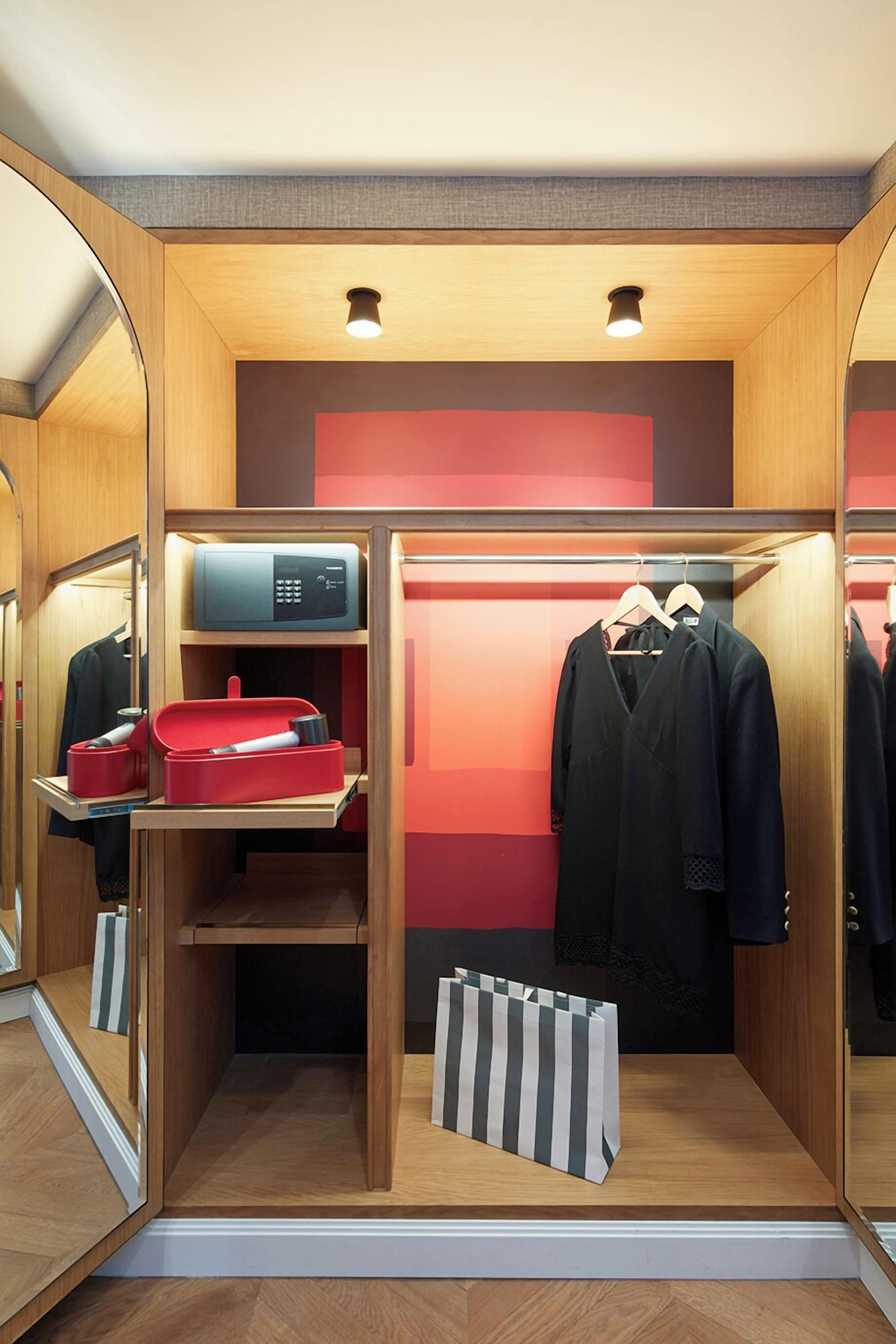 A compact, well-organized closet with mirrored doors, a microwave, and neatly arranged clothing and accessories.
