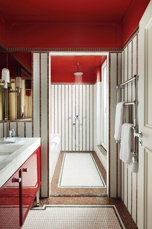 A modern bathroom with a red and white color scheme, a large mirror, a shower area, and a towel rack. - Villa-des-Prés (Paris)