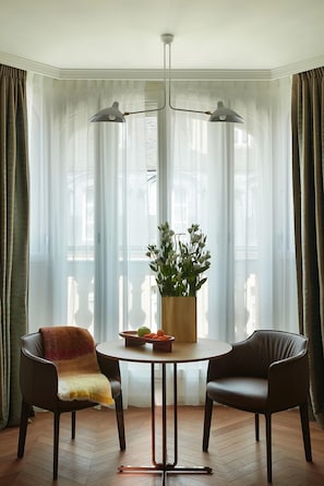 A dining area with a round table, two chairs, a vase with flowers, and a pendant light. - Villa-des-Prés (Paris)
