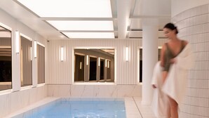 Ein Swimmingpool mit glasklarer, blauer Wasseroberfläche, umgeben von weißen Wänden und einer Decke mit Oberlichtern.