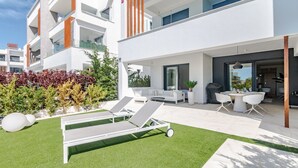 A modern apartment with a balcony, outdoor seating, and a well-maintained lawn. - Apartment 'Ground Floor 2bed Miradores Del Sol' with Shared Pool, Wi-Fi and Air Conditioning (Estepona)