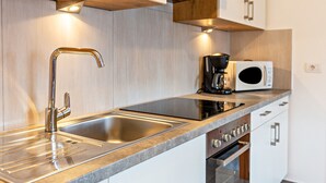 Une cuisine moderne dotée d’appareils électroménagers en acier inoxydable, d’un évier à deux bacs et de meubles de rangement en bois.
