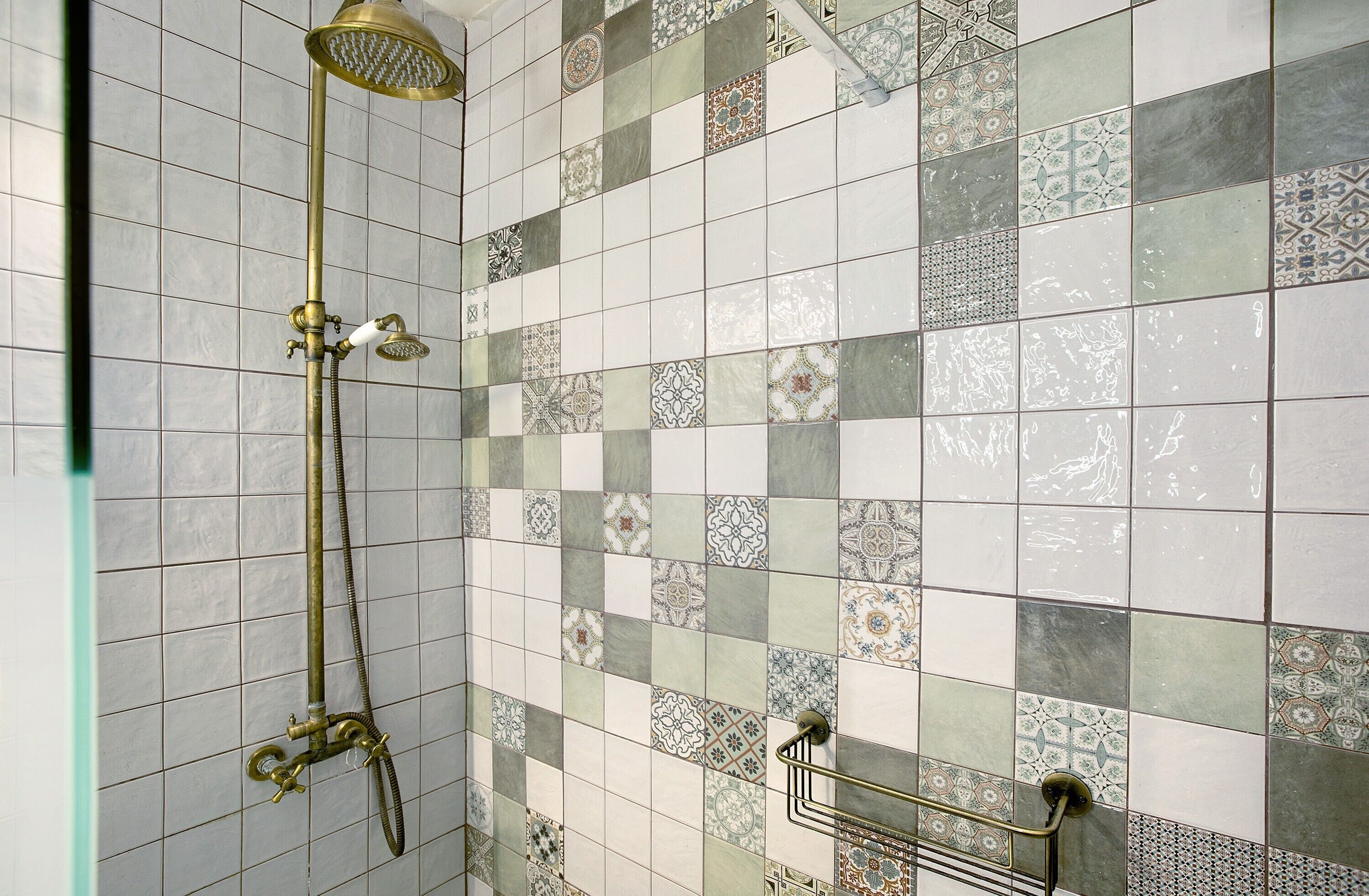 Baño con ducha, paredes de azulejos y barra de apoyo.