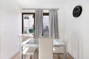 A dining area with a table and chairs, a window with curtains, and a wall clock. - Vacation Home 'Suite Deluxe Puerto Rico 11' with Shared Pool and Wi-Fi (Puerto Rico)