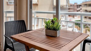 A wooden table with a potted plant on a balcony with a view of buildings. - Spacious 'Amplio Canet' Apartment with Shared Pool, Wi-Fi, and Air Conditioning (Canet de Berenguer)