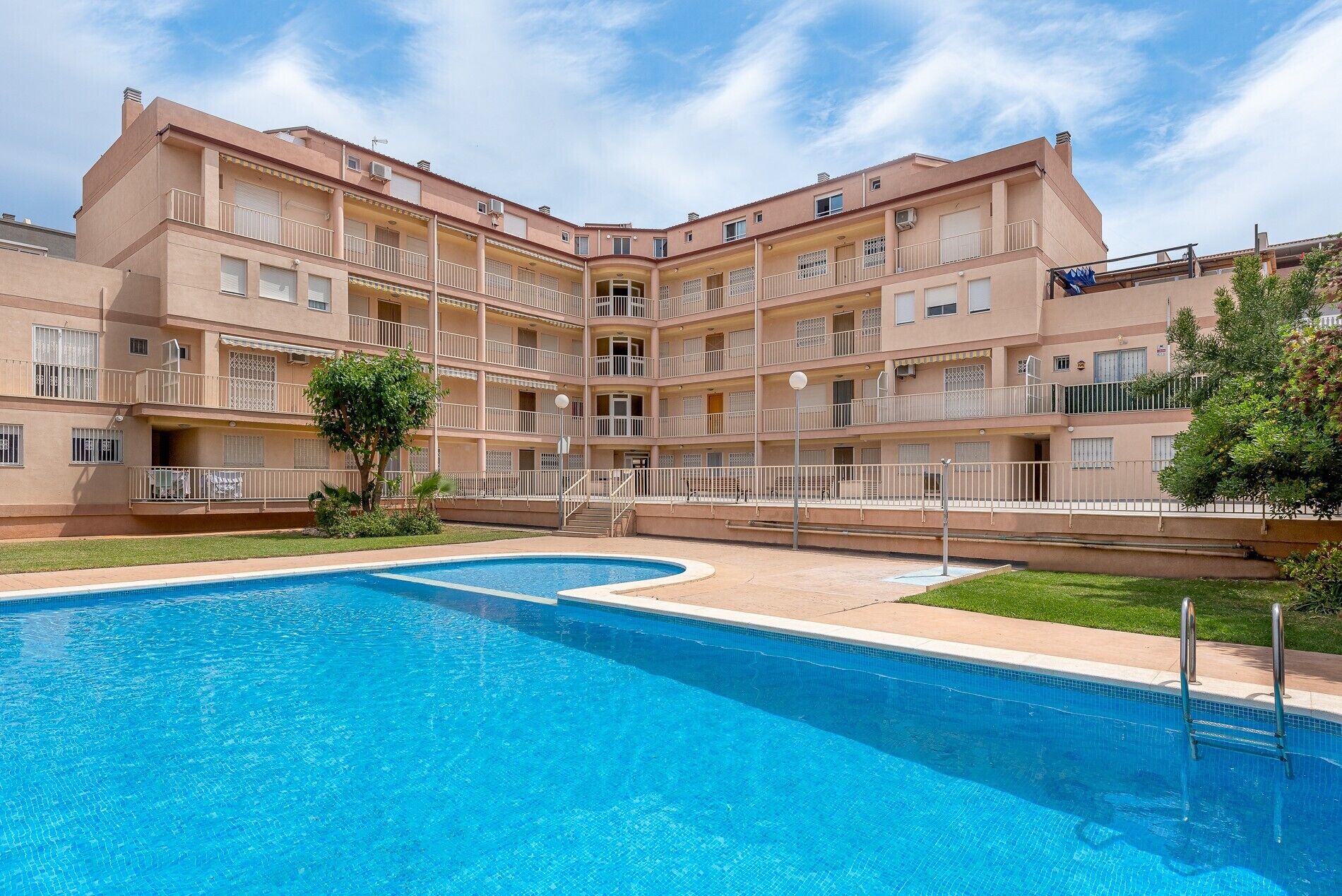 Un edificio de varios pisos con una piscina al frente.