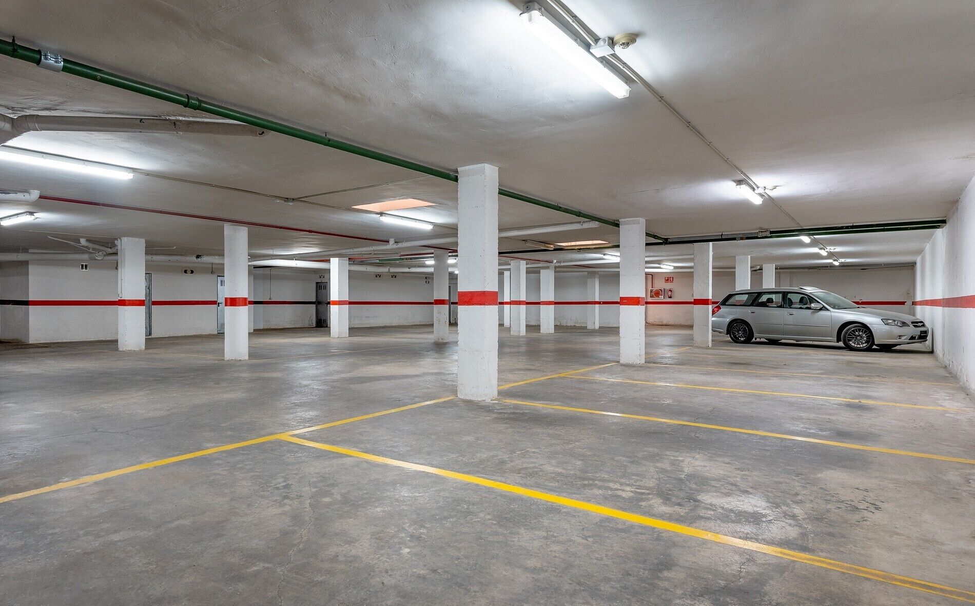 A multi-level parking garage with concrete floors, white pillars, and red and yellow parking lines.