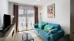 Un salon avec un canapé, un téléviseur, une table basse et un tableau accroché au mur.