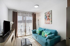 A living room with a sofa, a TV, a coffee table, and a painting on the wall.