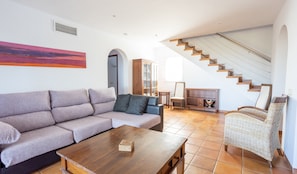 A living room with a sofa, coffee table, wicker chair, and a staircase. - Villa "Finesse Tipo 2" with Private Pool, 2 Private Terraces & Wi-Fi (Son Bou)