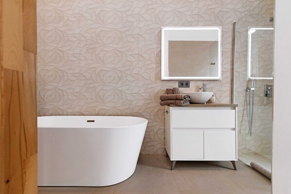 Une salle de bain moderne avec une baignoire sur pieds, un meuble-lavabo avec miroir et un espace douche.