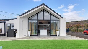 Une maison moderne, avec une façade blanche, de grandes fenêtres en verre et une pelouse bien entretenue.