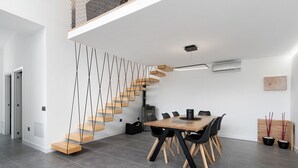 Un intérieur moderne comprenant un escalier, un coin repas et un climatiseur fixé au mur.