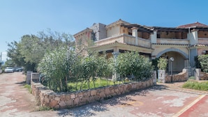 A two-story house with a stone wall and a paved driveway. - Holiday Home 'Villetta Sarda' with Private Terrace and Air Conditioning (san teodoro lu fraili)